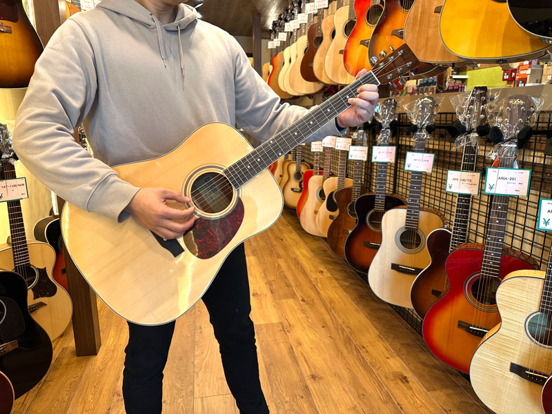 アコースティックギターを持つ店舗スタッフ